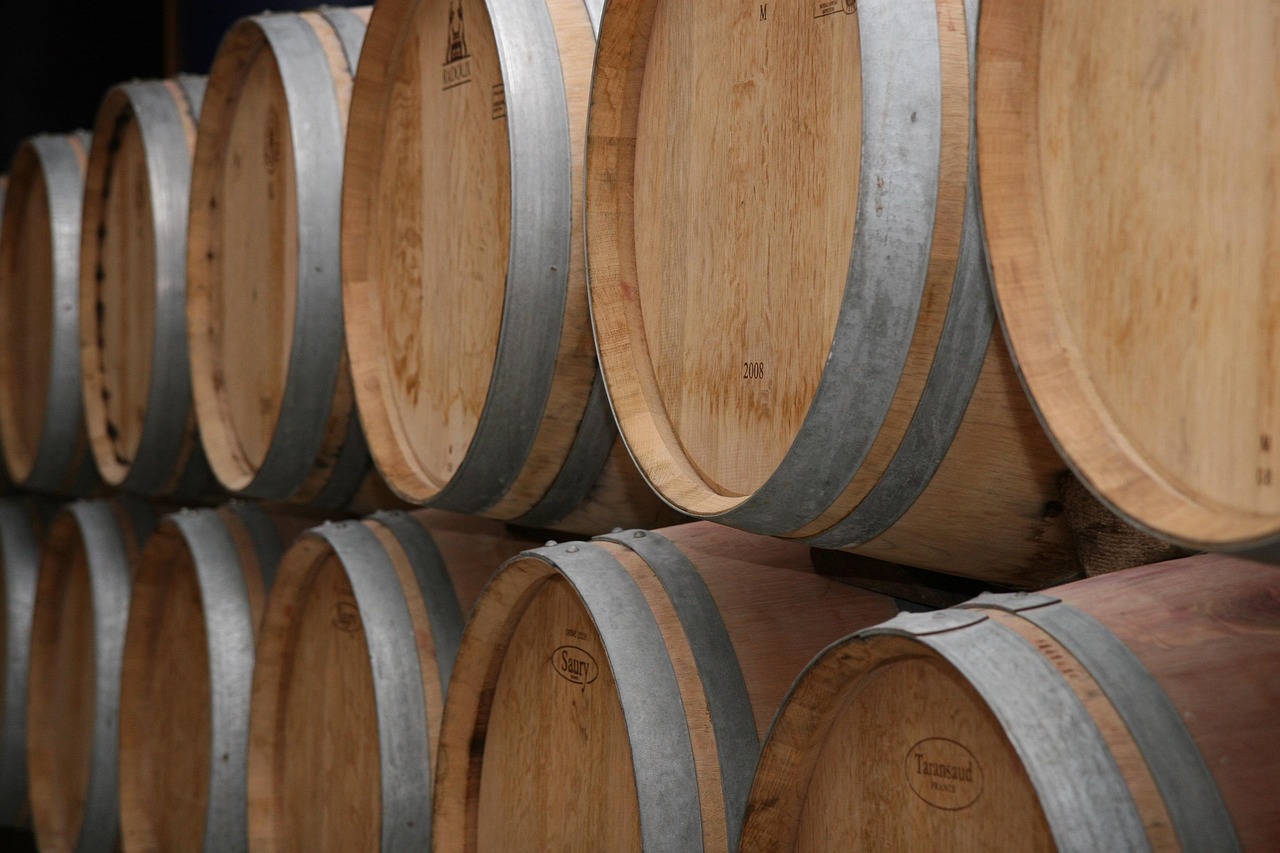 Oak barrels stacked in a winery cellar where wine is aged